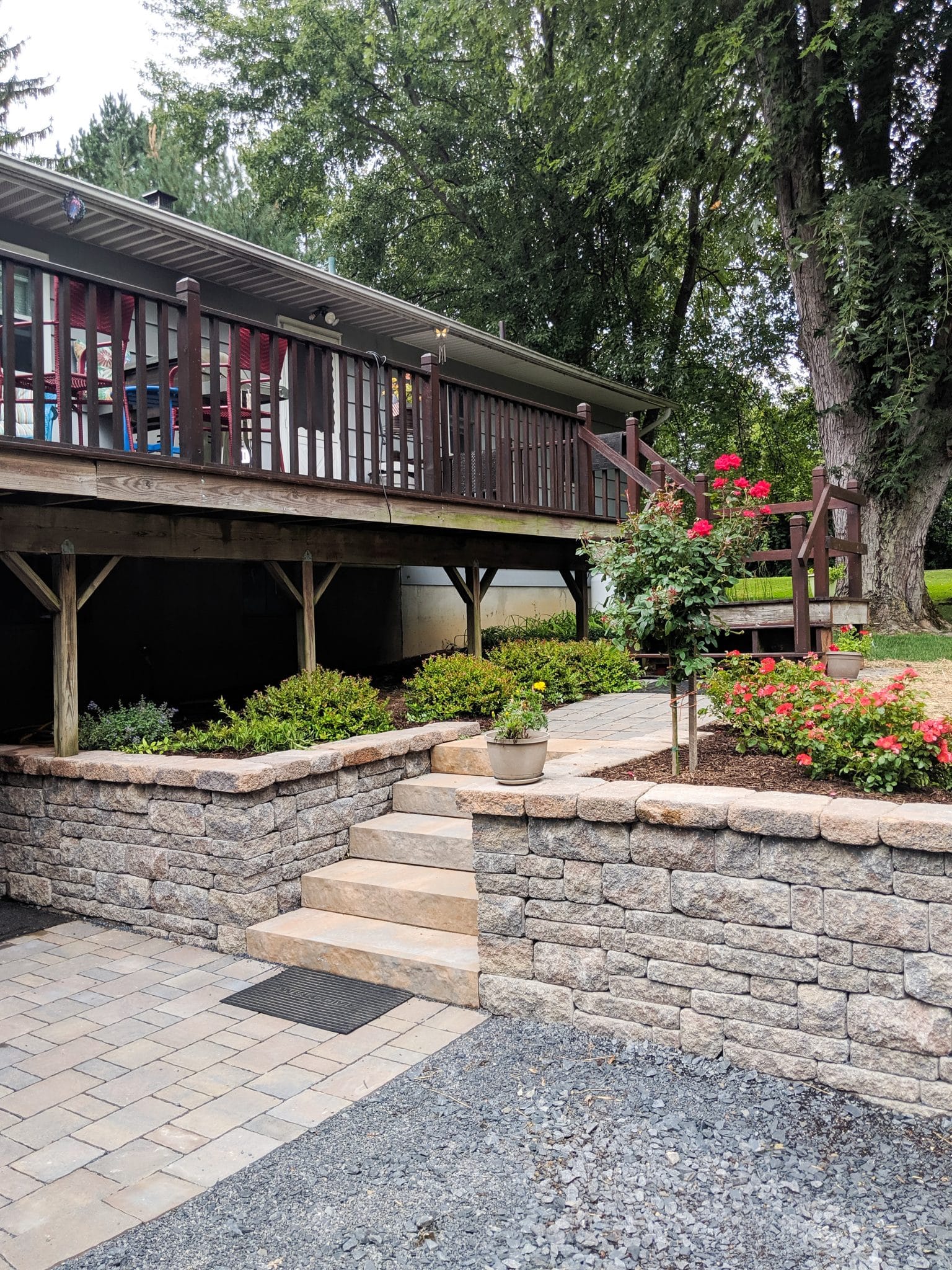 A stone-texture precast concrete Belgard Brookshire retaining wall, Belgard steps, walkway, and paver driveway with native plantings in New Paltz, NY, installed by Masseo Landscape, Inc.