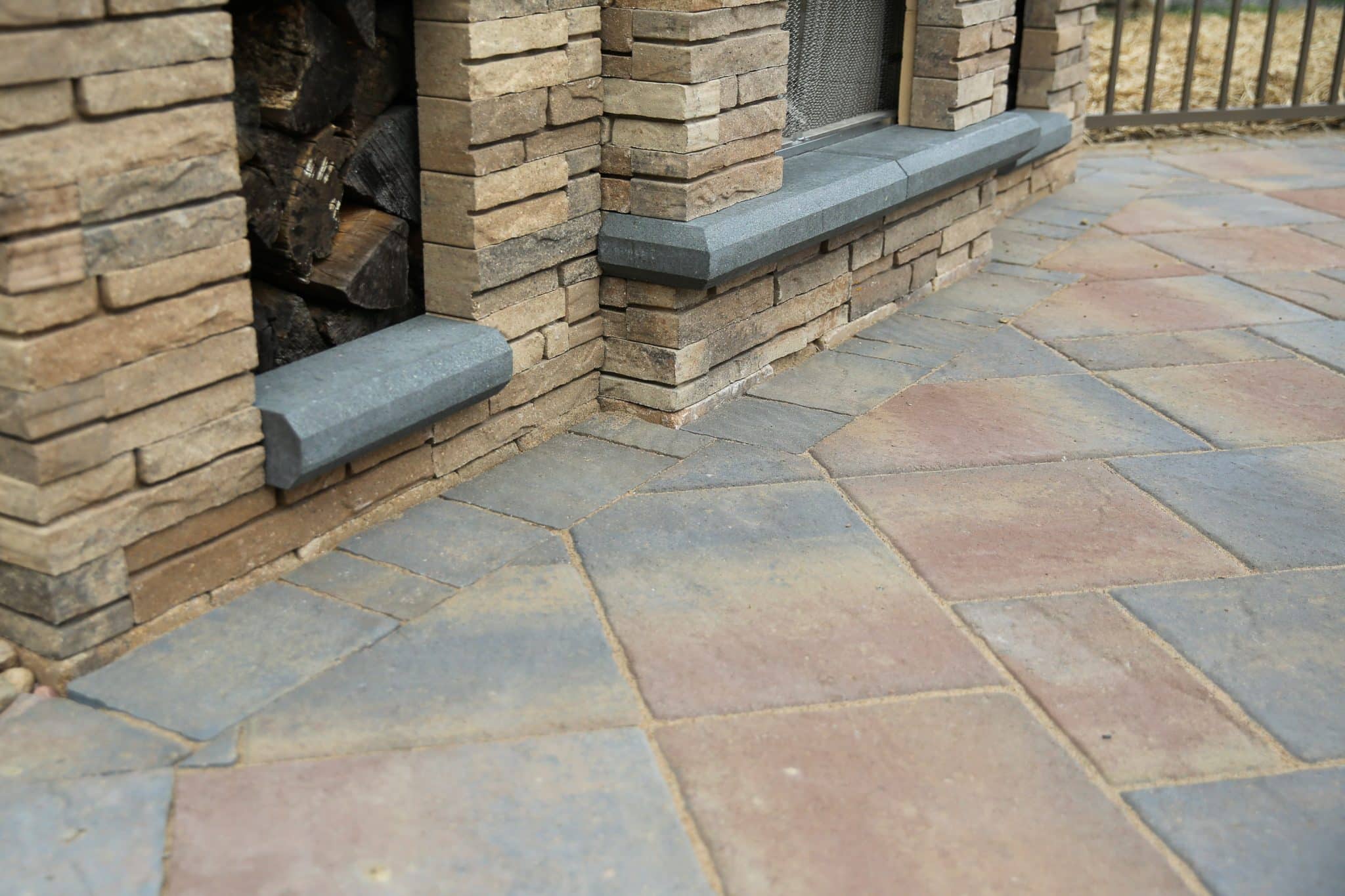 A detail showing the Belgard precast concrete paver patio with a contrasting border cut to fit around the base of a precast concrete fireplace.