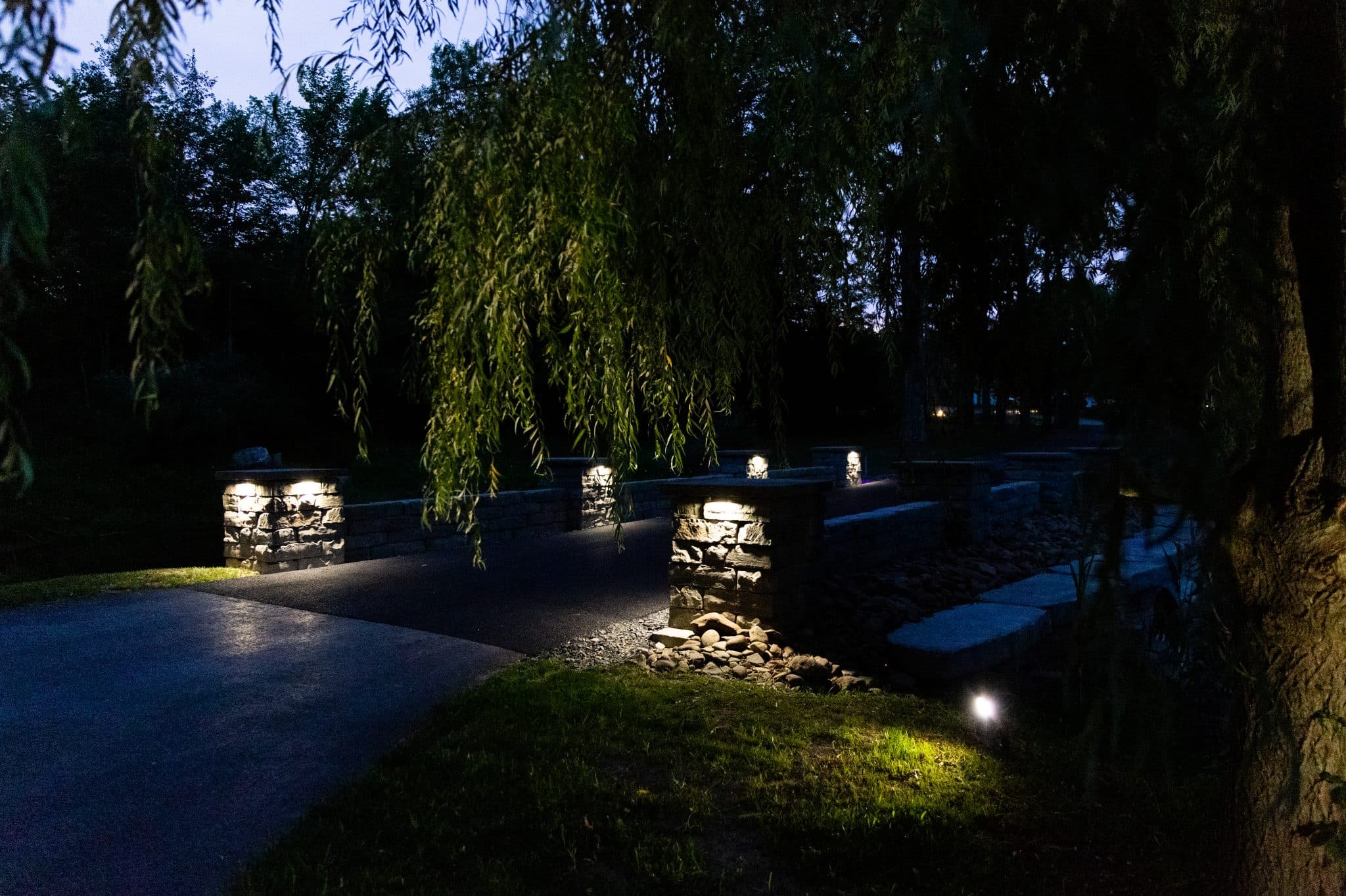 A driveway flanked by two precast concrete walls with pillars with lights on them in Gardiner, NY.