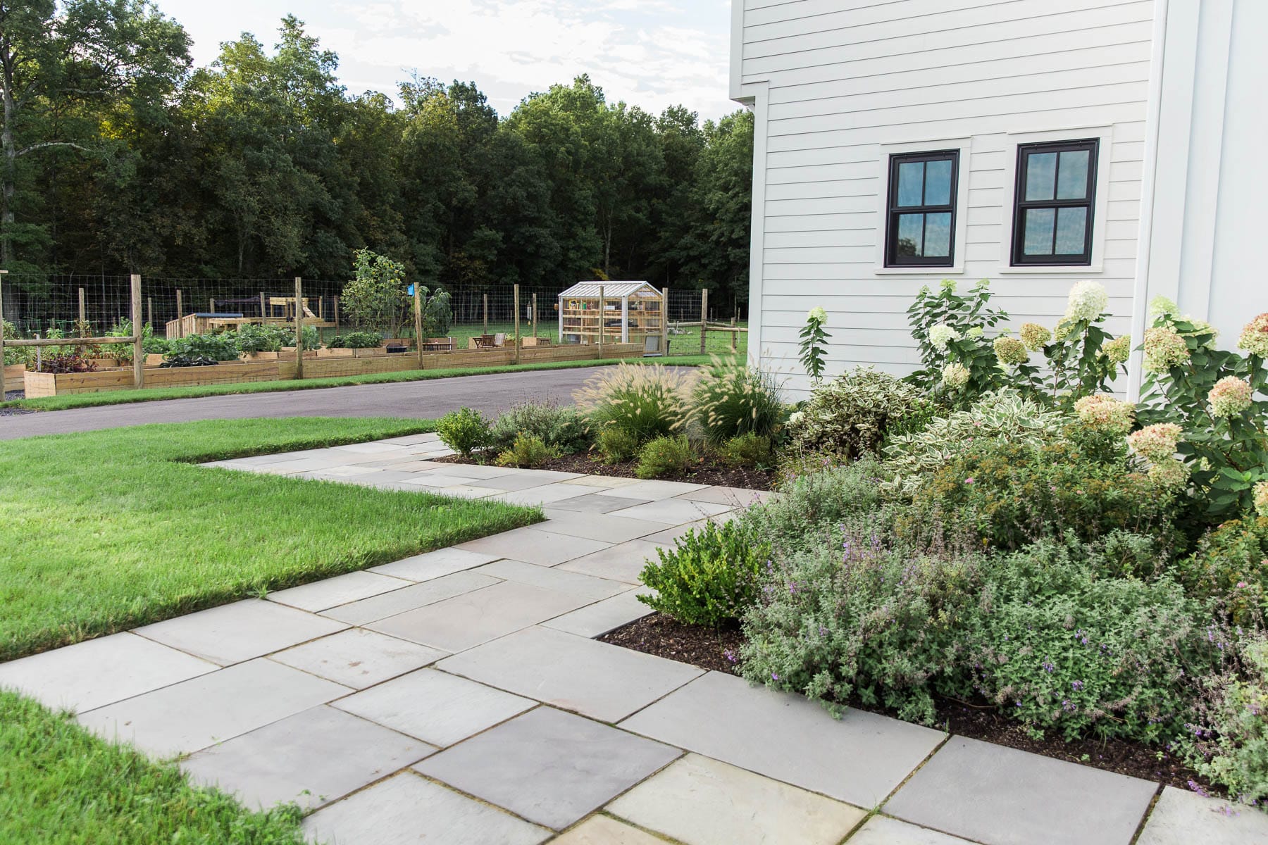 A rectilinear bluestone walkway with native landscape plantings designed by Masseo Landscape, Inc. in Gardiner, NY