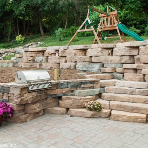 An outdoor kitchen area featuring Rosette Hardscapes wall stone.