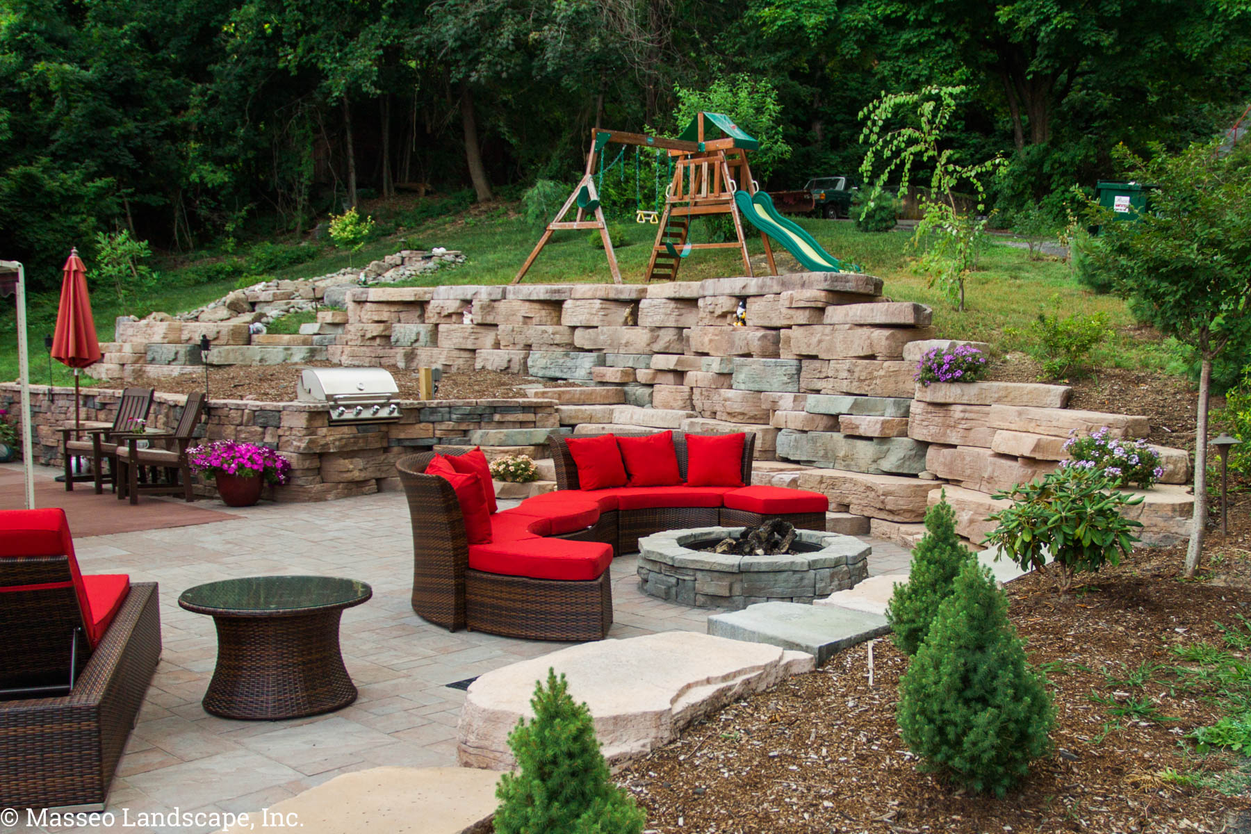 An outdoor living space with a grill, fire pit, and patio installed in Highland, NY by Masseo Landscape, Inc., best Ulster County landscape contractors.