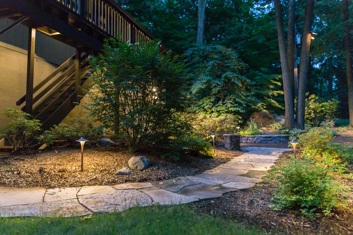 Outdoor lighting scheme in yard with stone walkway and planting by Masseo Landscape, Inc.