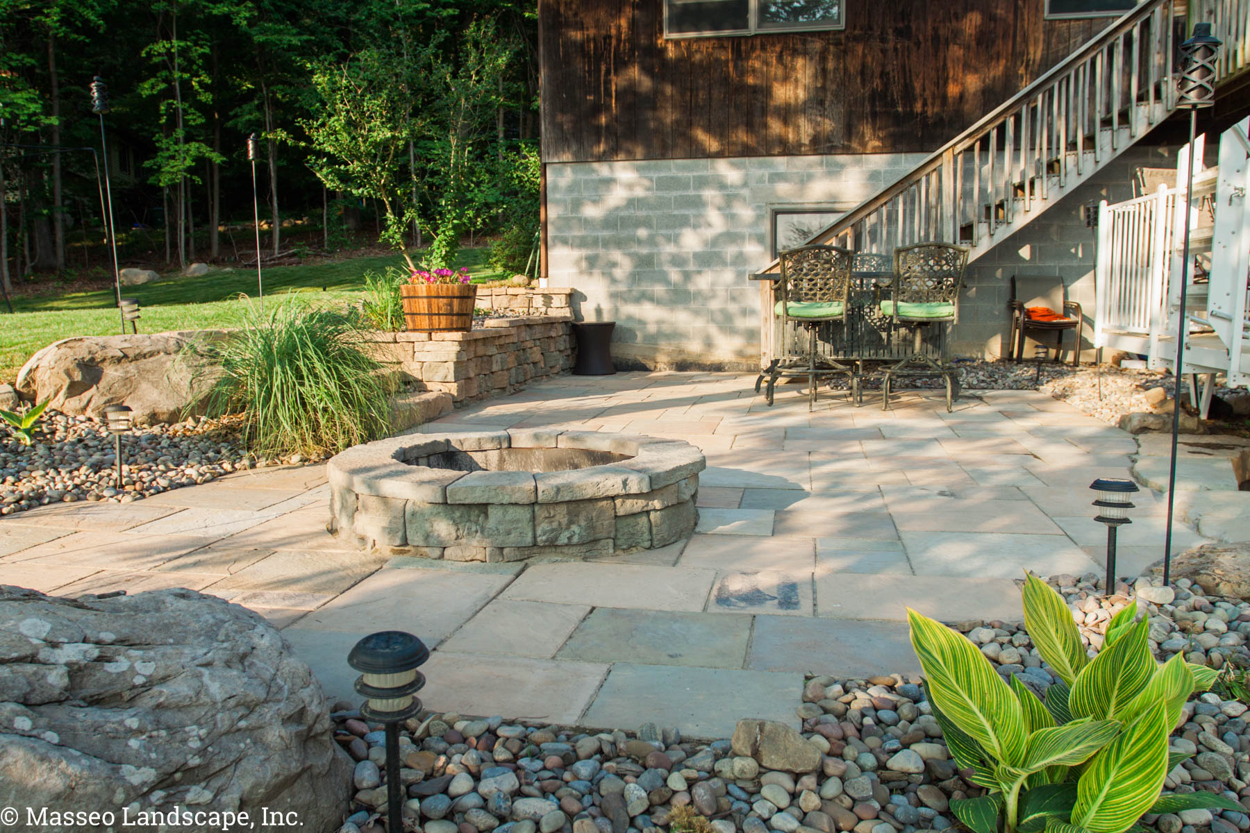 Poolside patio with a fire pit designed and installed by Masseo Landscape, Inc.